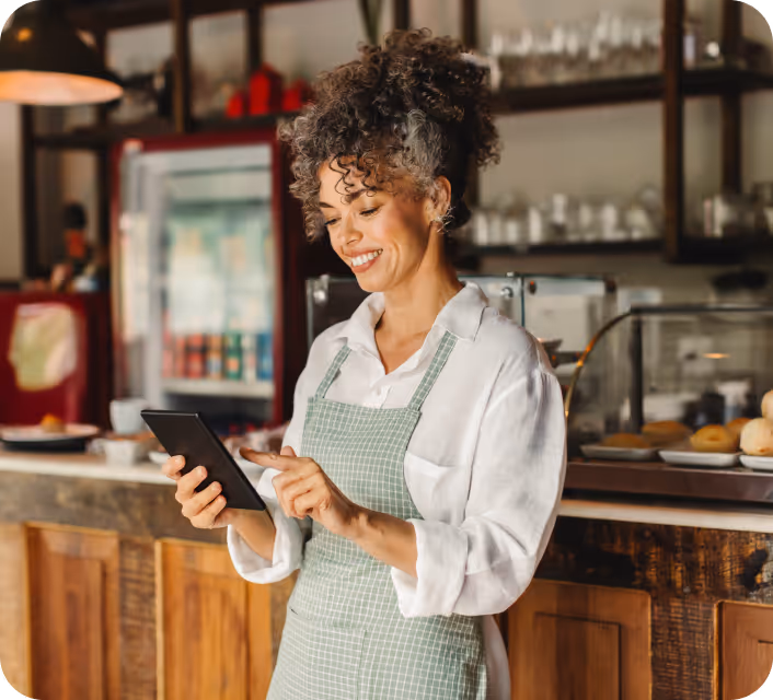 Shop owner on a tablet next to a store checkout with the Local Delivery option selected